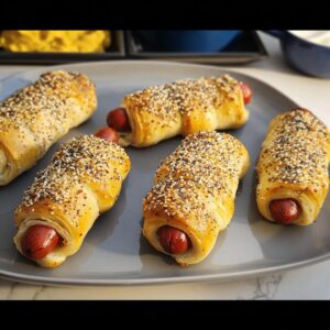 Five Everything-Bagel Mummy Dogs on a gray plate, topped with sesame seeds.