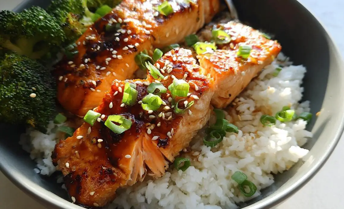 Bowl of honey-garlic salmon fillets served over rice with broccoli.