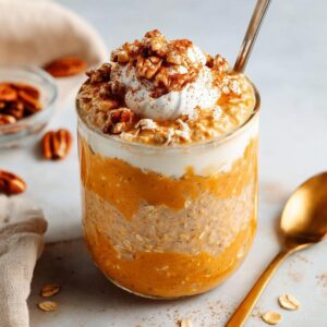 Pumpkin pie overnight oats topped with whipped cream, pecans, and cinnamon.