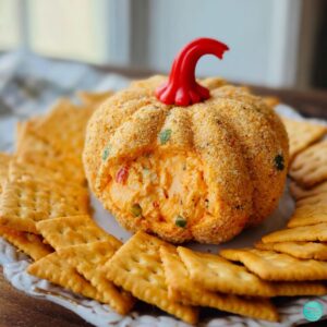 Pumpkin-shaped cheese ball surrounded by Ritz crackers on a platter.