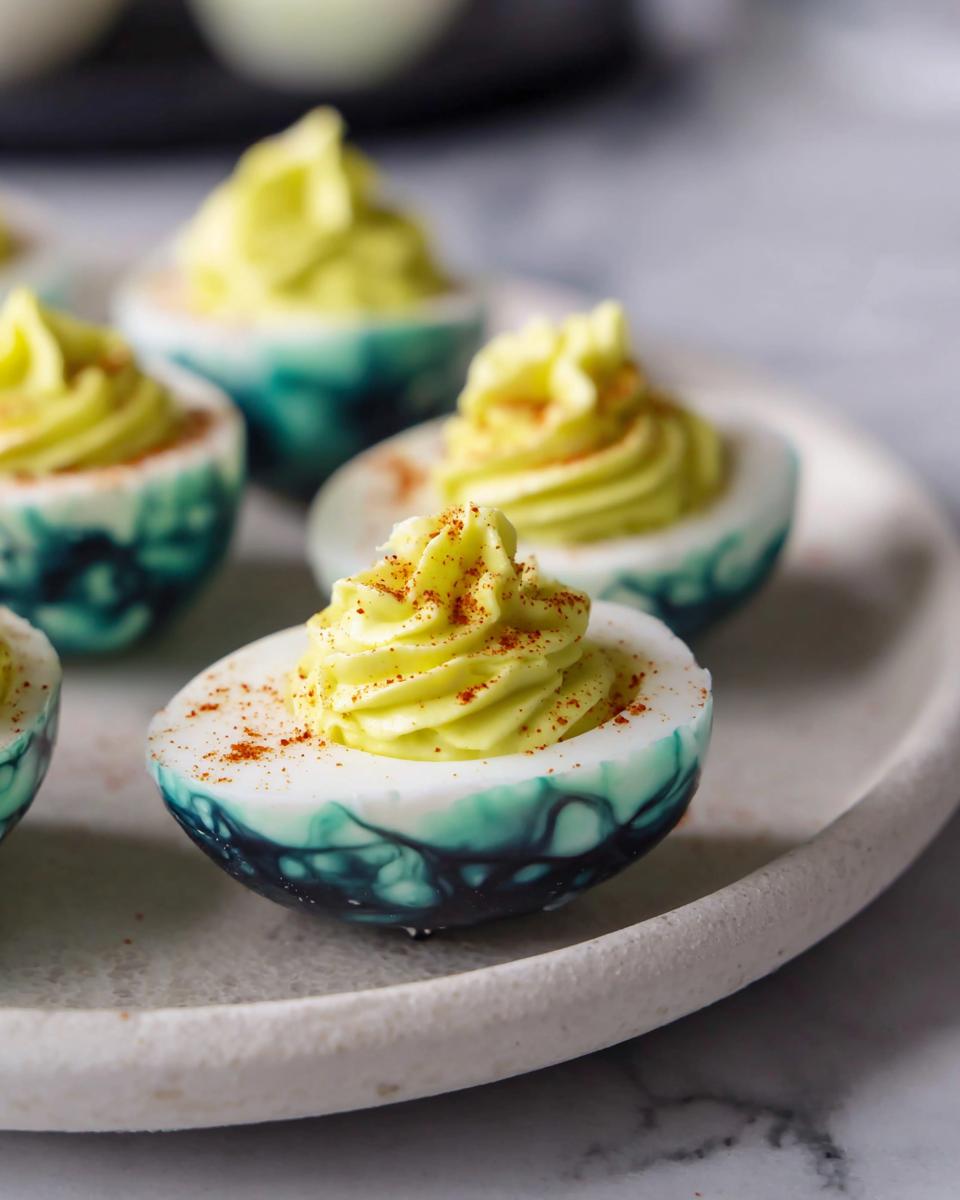 Colorful spider deviled eggs topped with green filling and paprika.