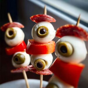 Spooky Caprese bites featuring mozzarella eyeballs, olives, and salami.