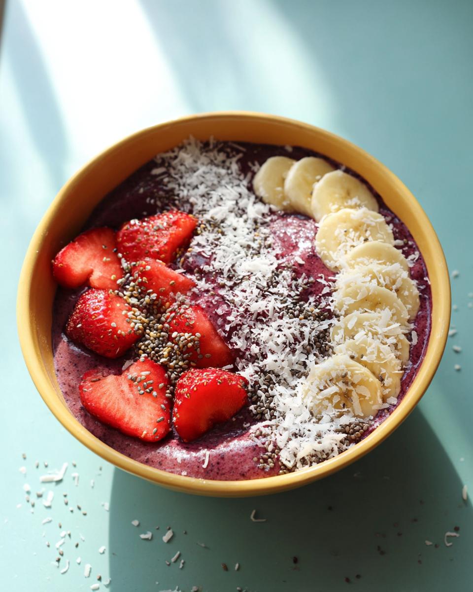 A vibrant smoothie bowl topped with strawberries, bananas, and coconut.